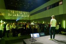 Ung mann på scenen med mange publikummere i salen