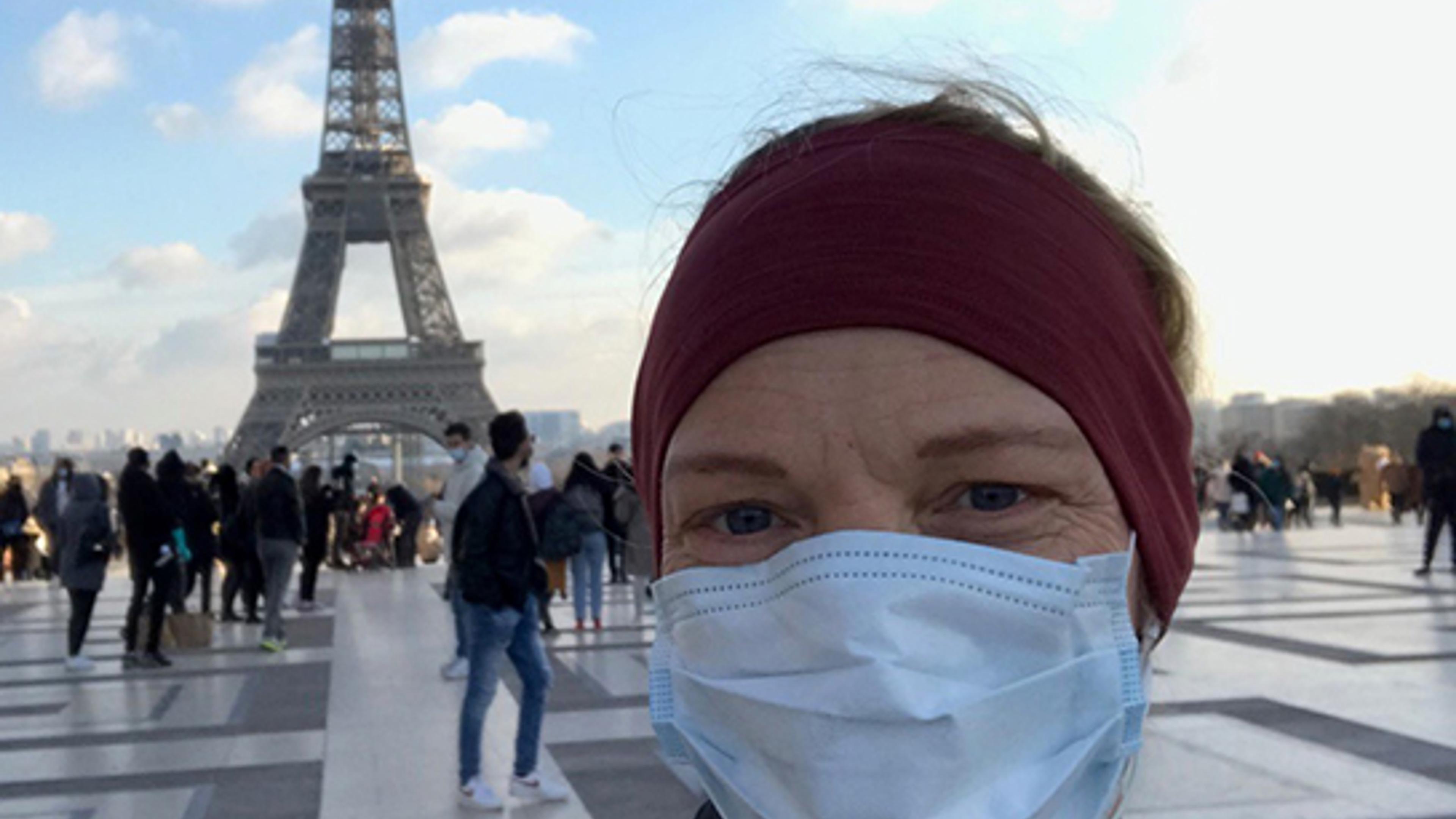 Kvinne med munnbind foran Eiffeltårnet
