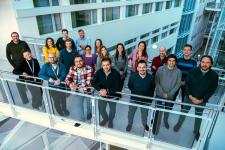 En gruppe mennesker står samlet på en bro innendørs