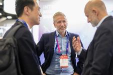 Tre menn i dress snakker sammen