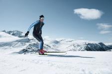 Mann går langrenn på høyfjellet i solskinn