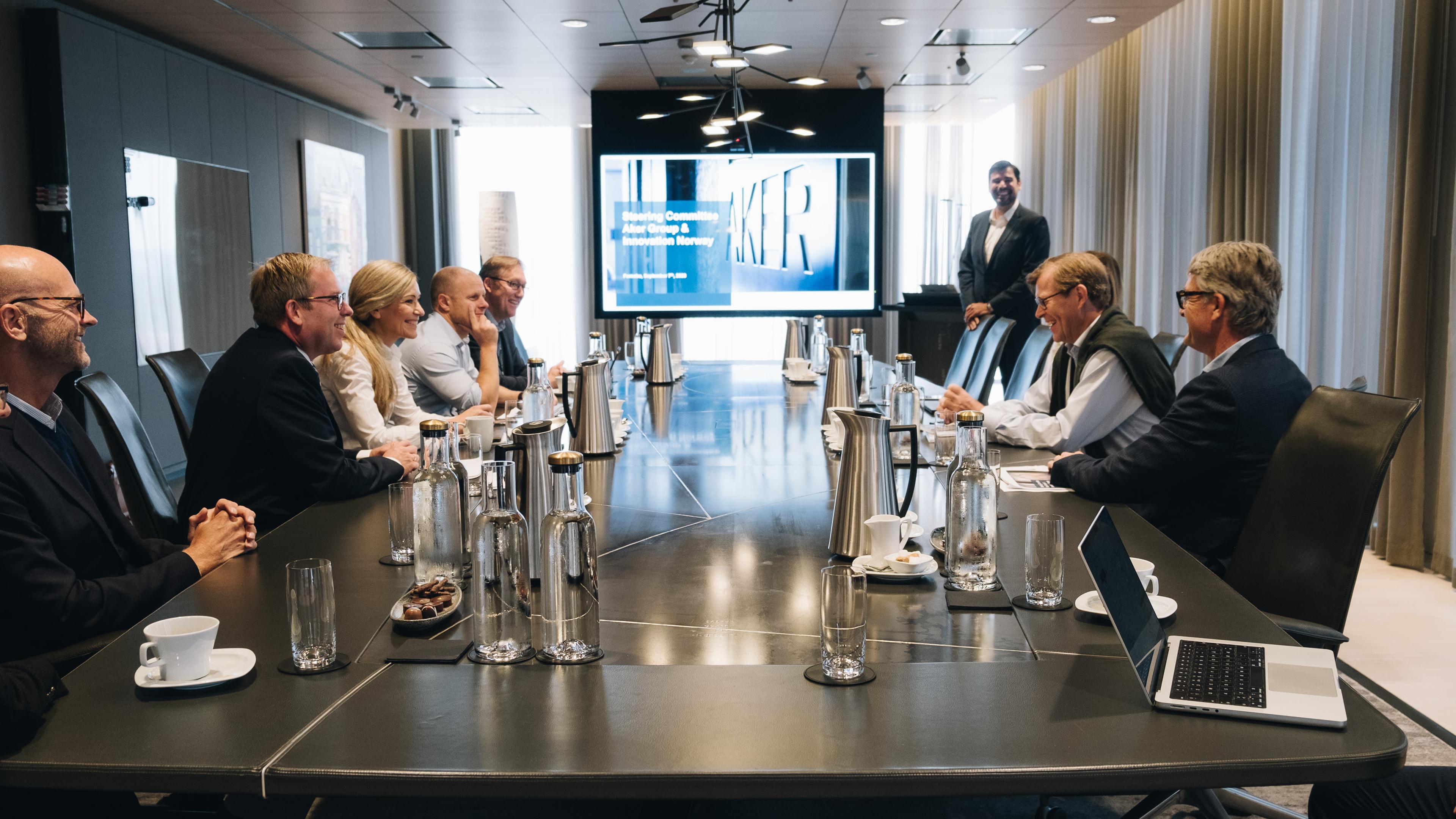Ledelsen i Aker ASA og Innovasjon Norge sitter rundt et møtebord og diskuterer lystig.