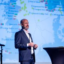 En mann på scenen står foran et verdenskart