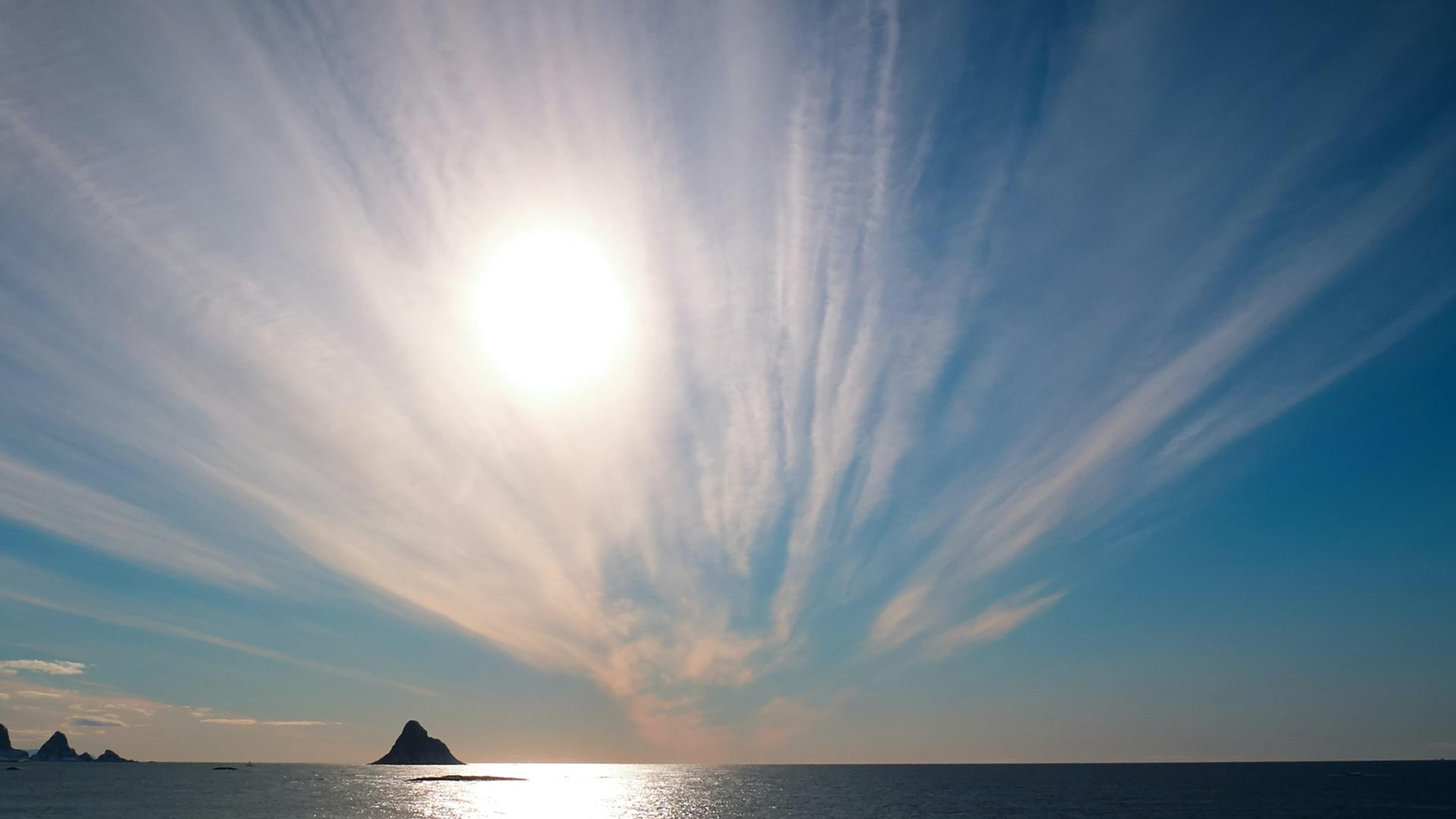 Sol over hav med små pyramide-formede fjelløyer