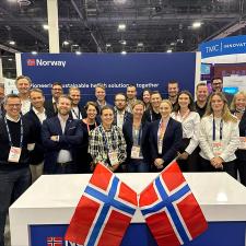 En gruppe mennesker med norske flagg rundt seg