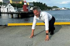 En mann later som han står i startblokken og skal løpe ute.