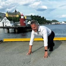 En mann later som han står i startblokken og skal løpe ute.