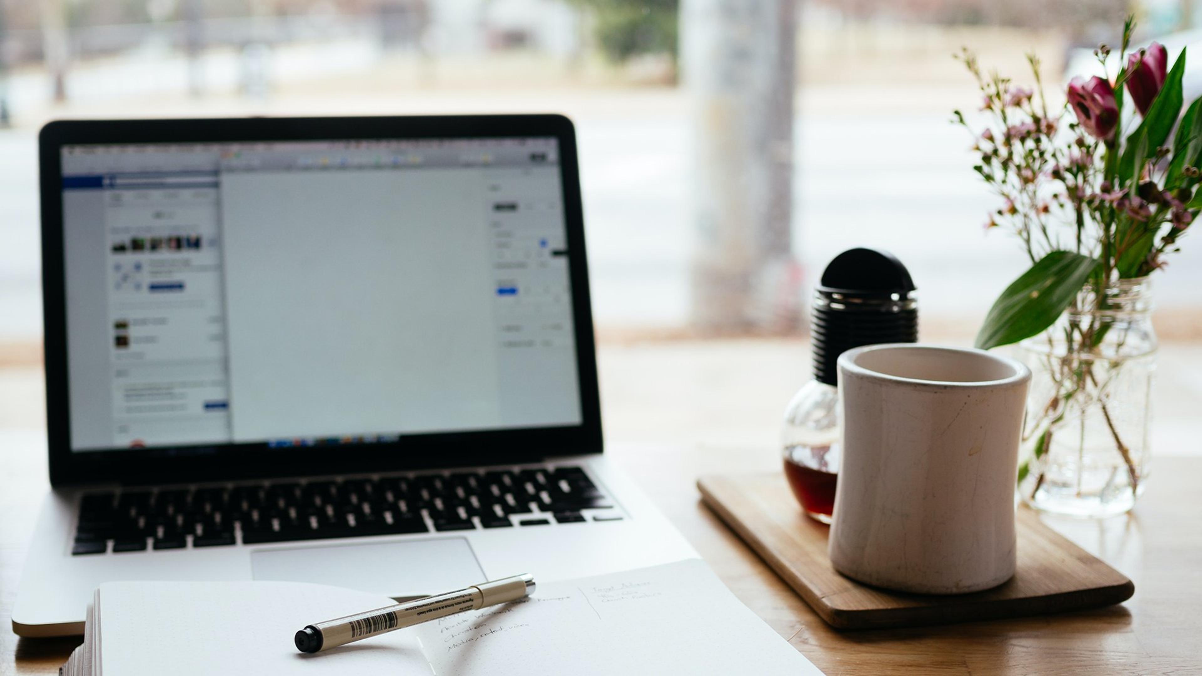 Laptop og kaffekopp på et arbeidsbord