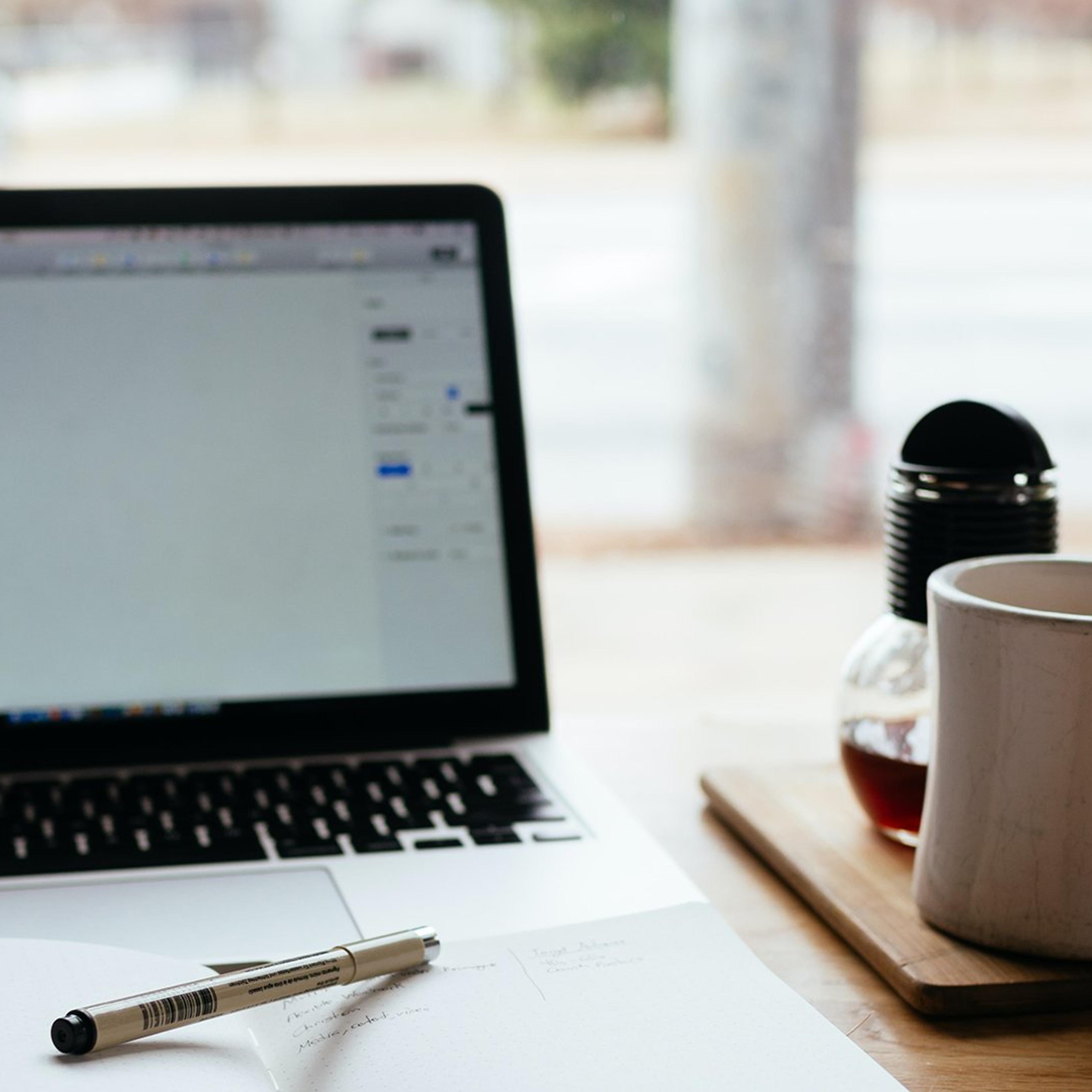 Laptop og kaffekopp på et arbeidsbord