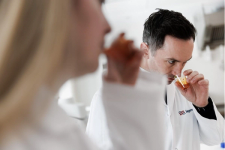 To personer i hvite frakker på et laboratorium som lukter nedi hver sitt glass