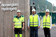 Tre personer står utendørs ikledd gule vester og hvite hjelmer