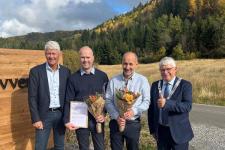 Fire menn smiler til fotografen. To holder et diplom og blomster.