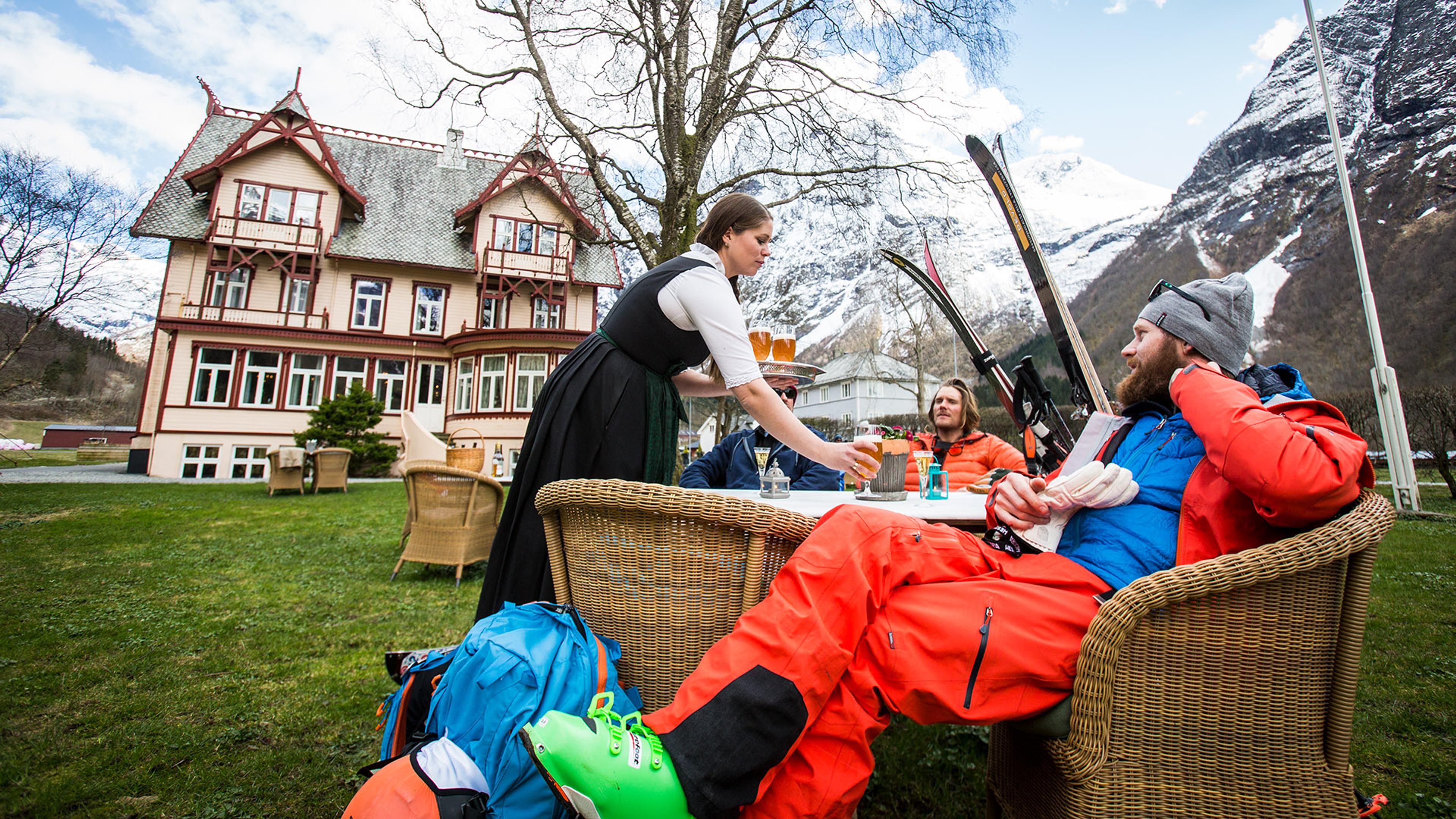 Skiløpere som nyter en drikk utenfor et erverdig gammelt hus i Norangsfjorden