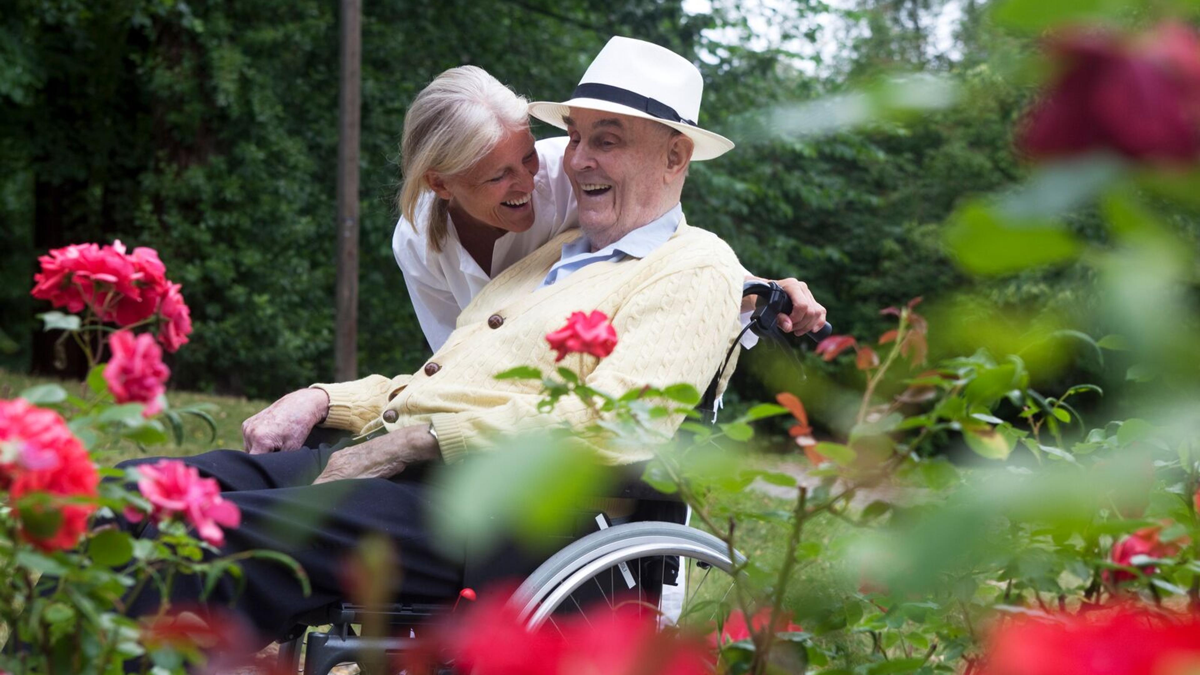 Et eldre par som nyter deilig vær i en hage