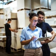 Kvinne viser noe til en mann på en tablet i et eksportlager