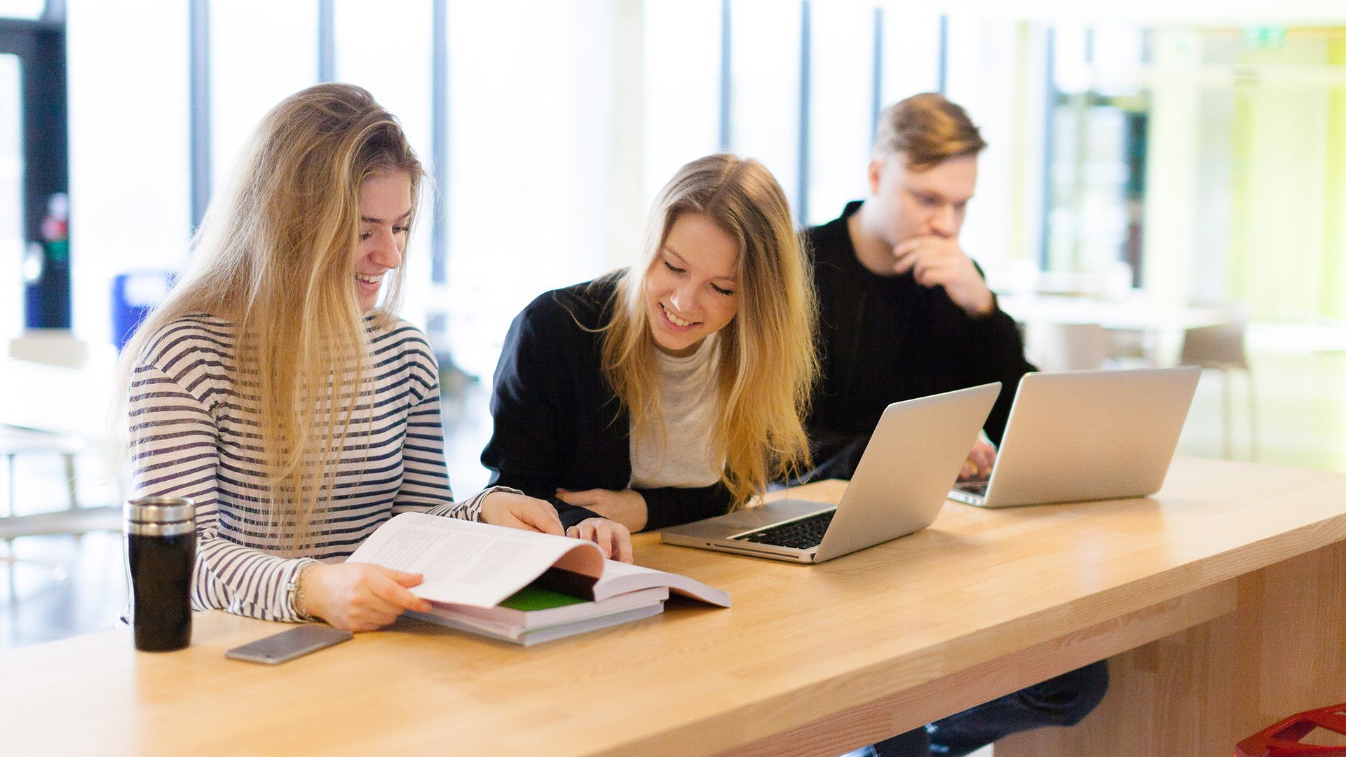 Tre studenter som sitter sammen og gjør skolearbeid