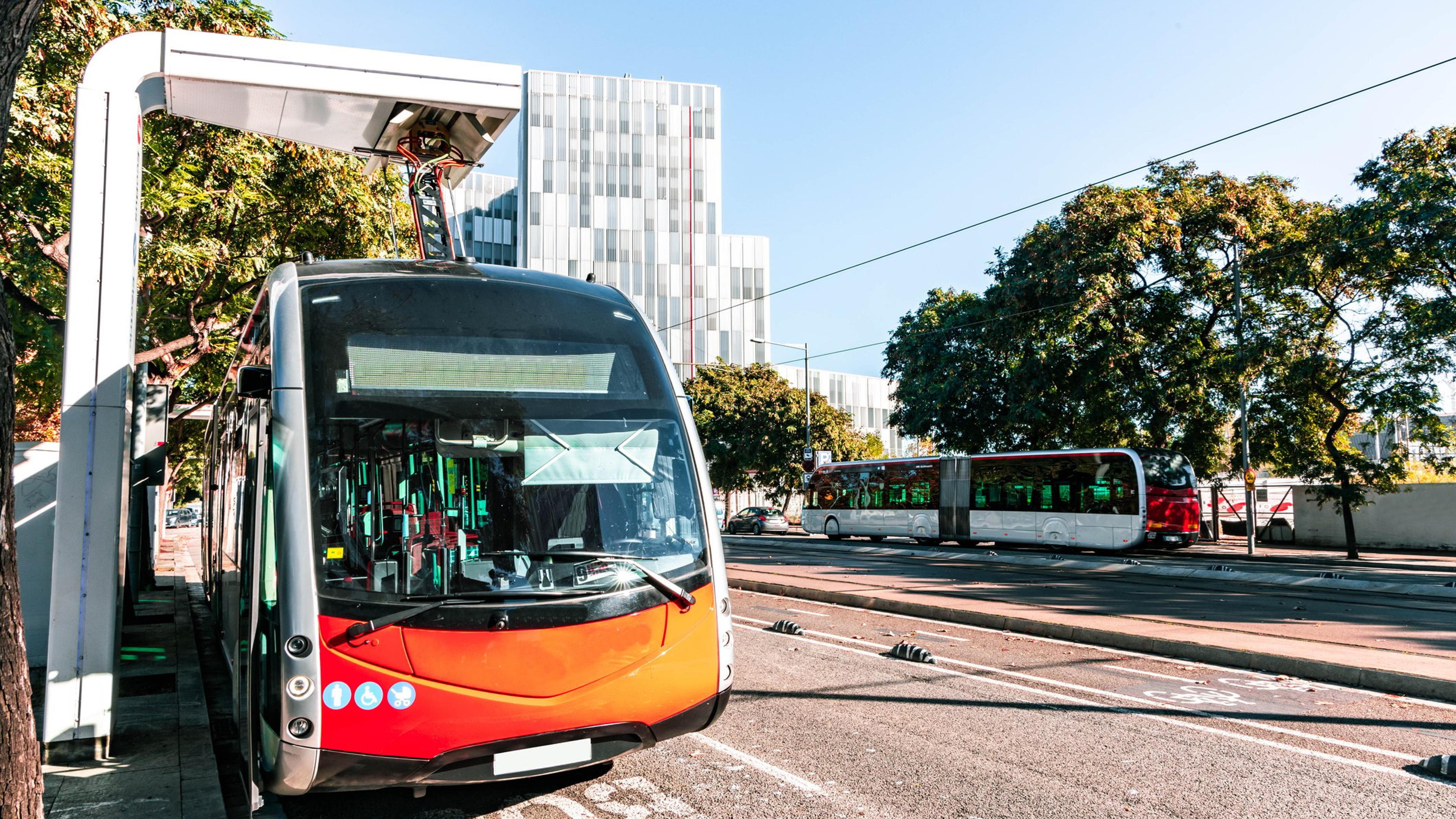 Ny leddet elektrisk buss gjør hurtiglading i ladestasjonen, ved enden av ruten innenfor lavutslippssonen i Barcelona sentrum. Spania.