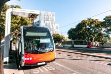 Ny leddet elektrisk buss gjør hurtiglading i ladestasjonen, ved enden av ruten innenfor lavutslippssonen i Barcelona sentrum. Spania.