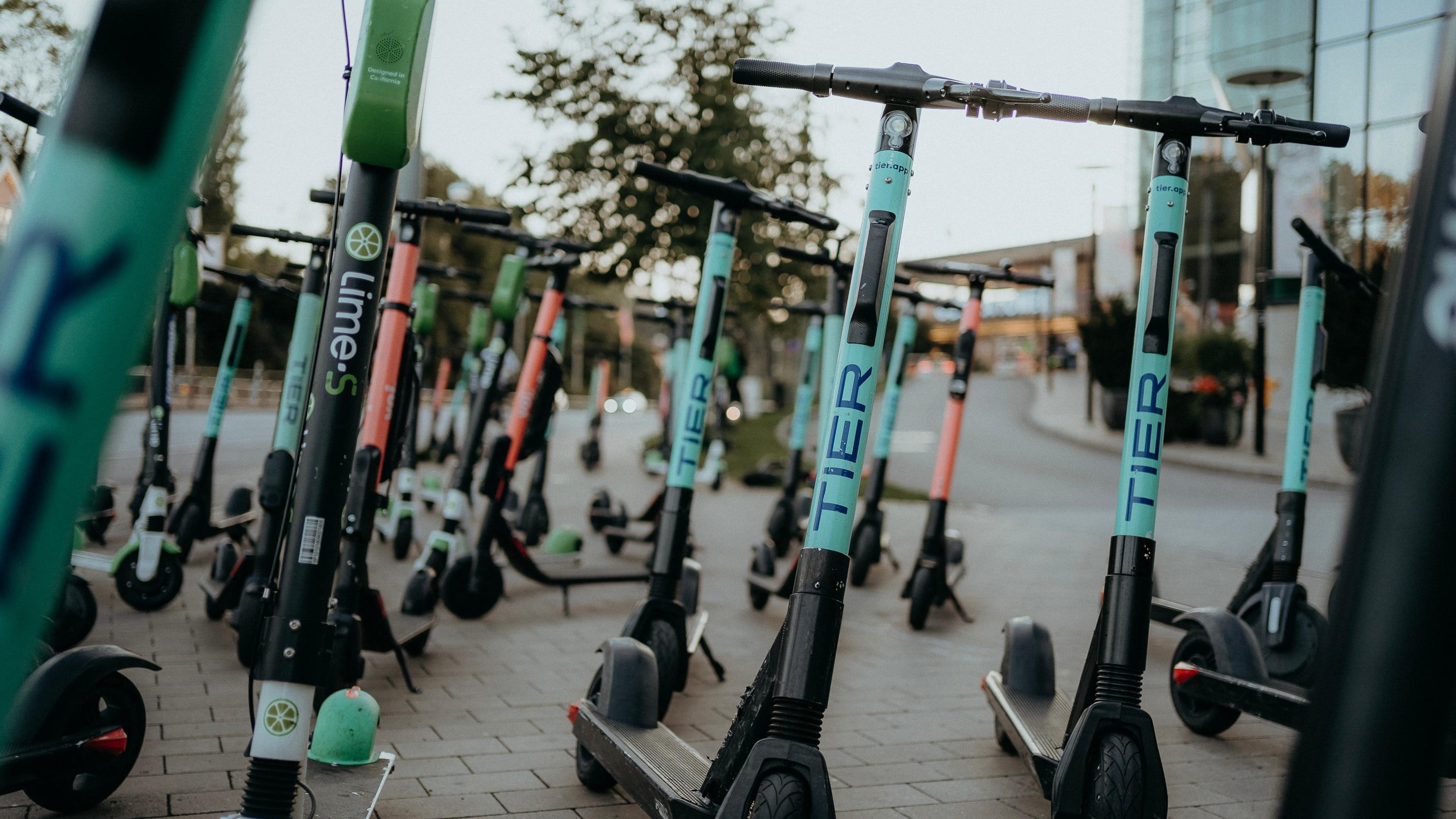 En rekke el-skootere som står parkert i svensk by