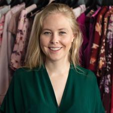 Portrett av kvinne og kjoler som henger bak henne