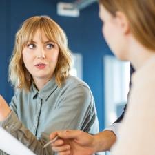 En kvinne forklarer noe til en annen kvinne som noterer ned