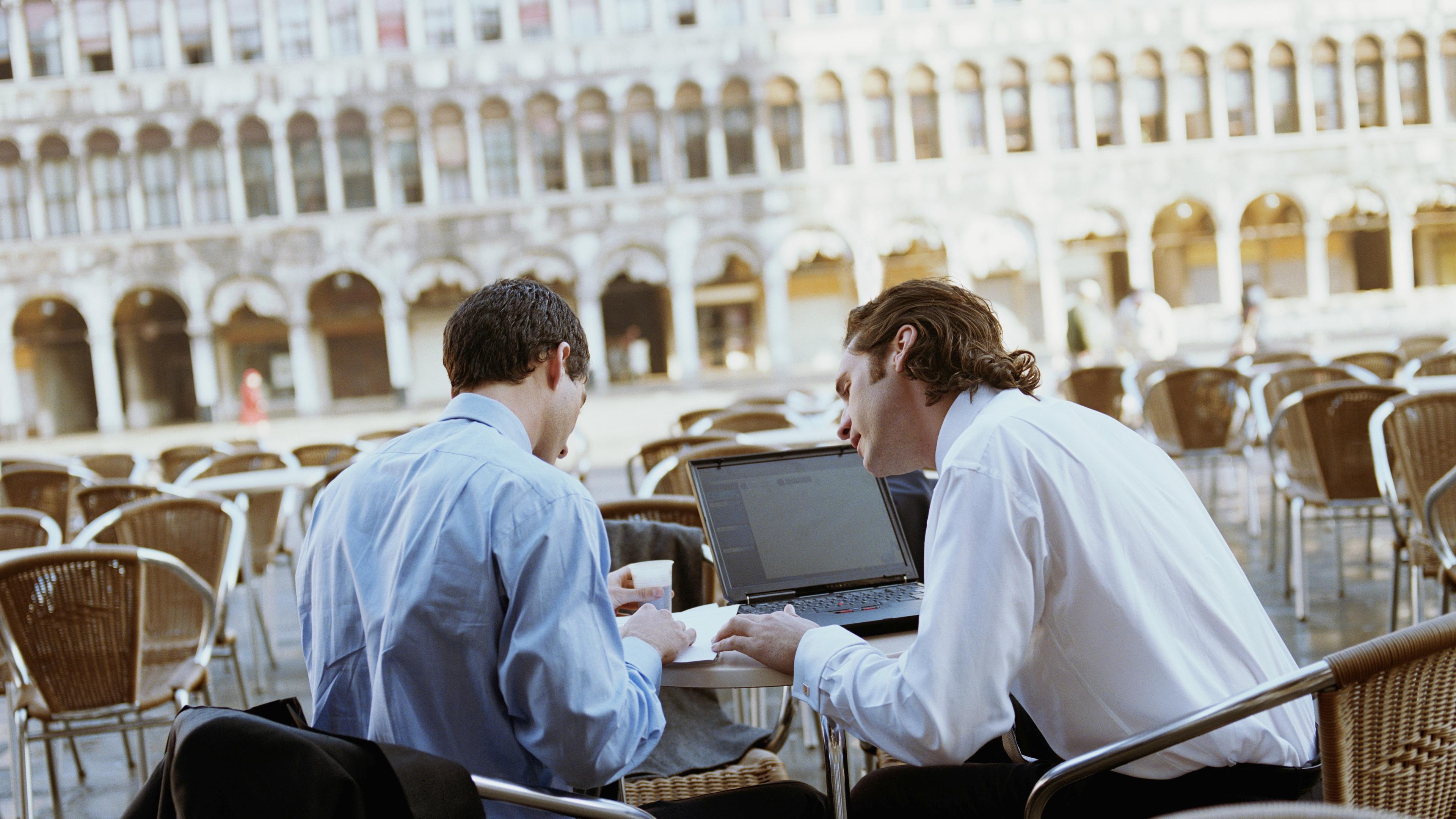 To forretningsmenn med laptop på kafe i Venezia i Italia