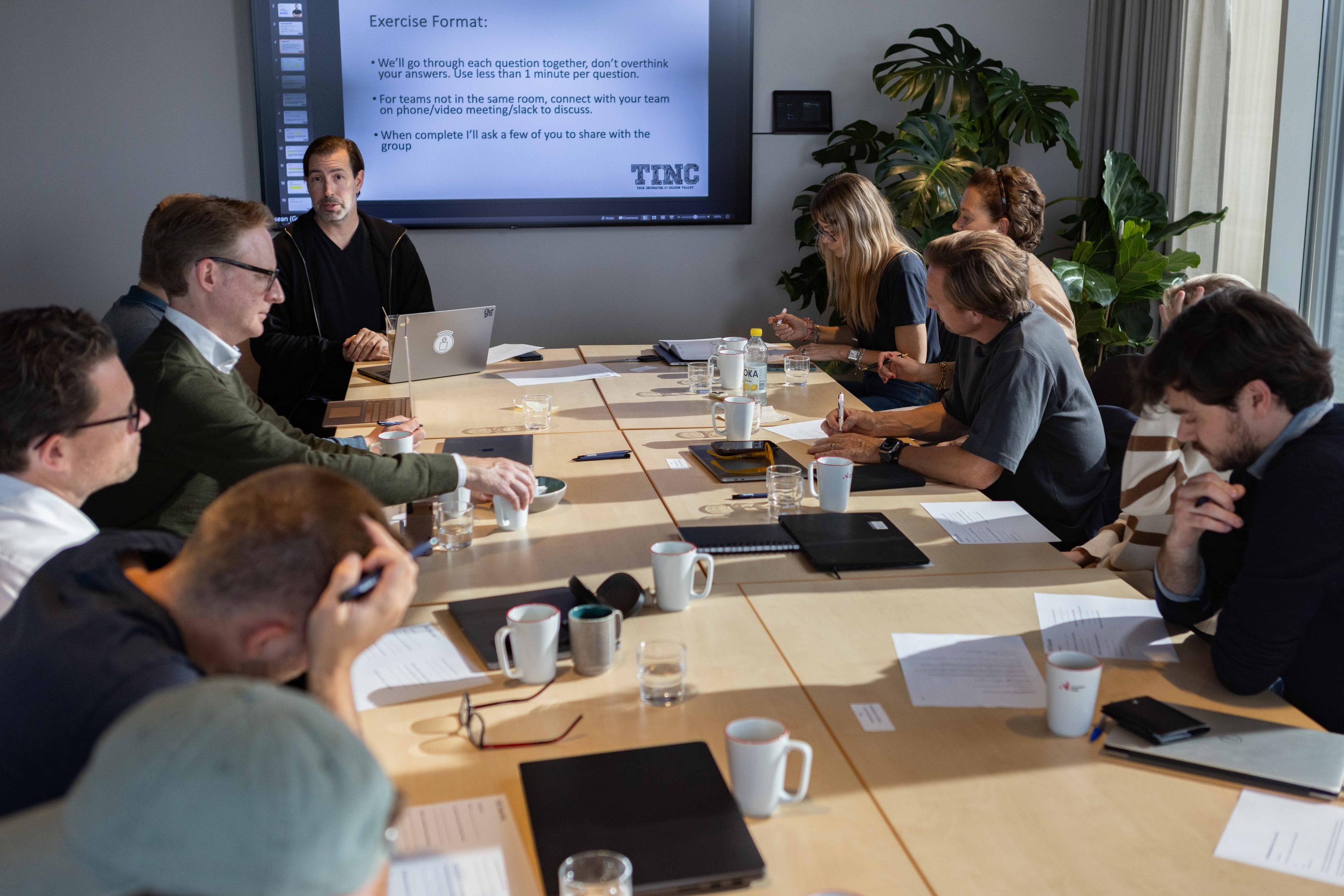 Personer sitter rundt et bord og arbeider