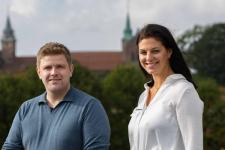 En mann og en dame smiler til fotografen