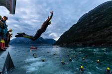 Athlete jumps into water filled with other competitors