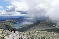 Personer som går til Gaustatoppen i skiftende vær