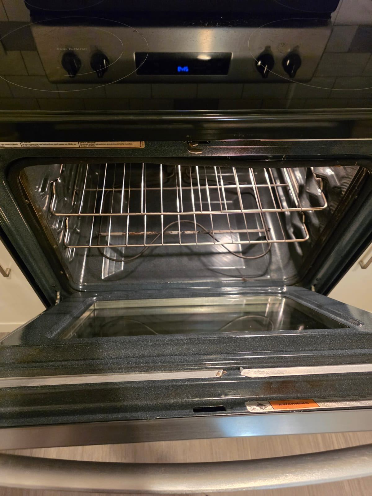 The inside of an open oven with clean racks, floor and door glass.