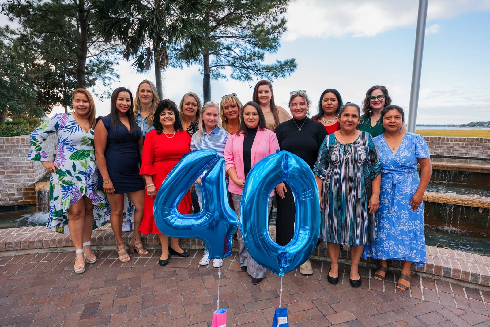 Teresa, the owner, in a red dress with a group of women behind blue "4" and "0" balloons.