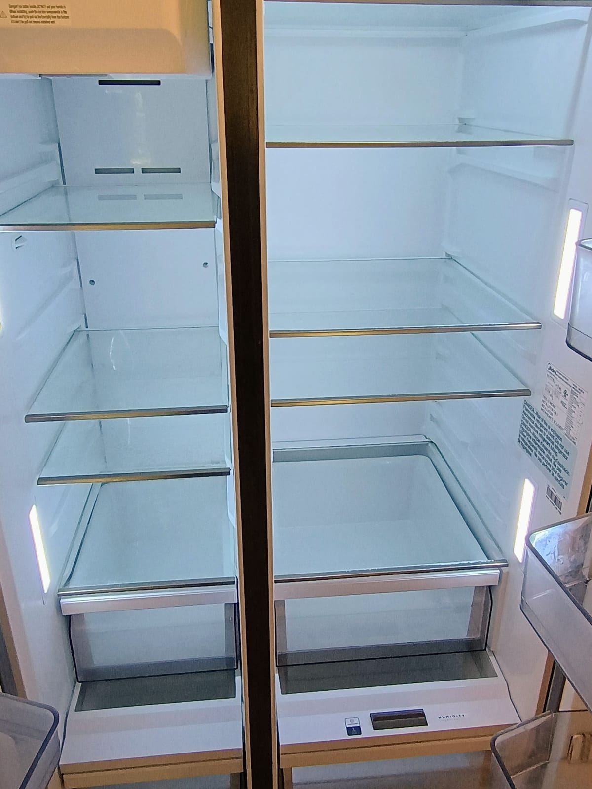 An open, empty side-by-side refrigerator with clean glass shelves.