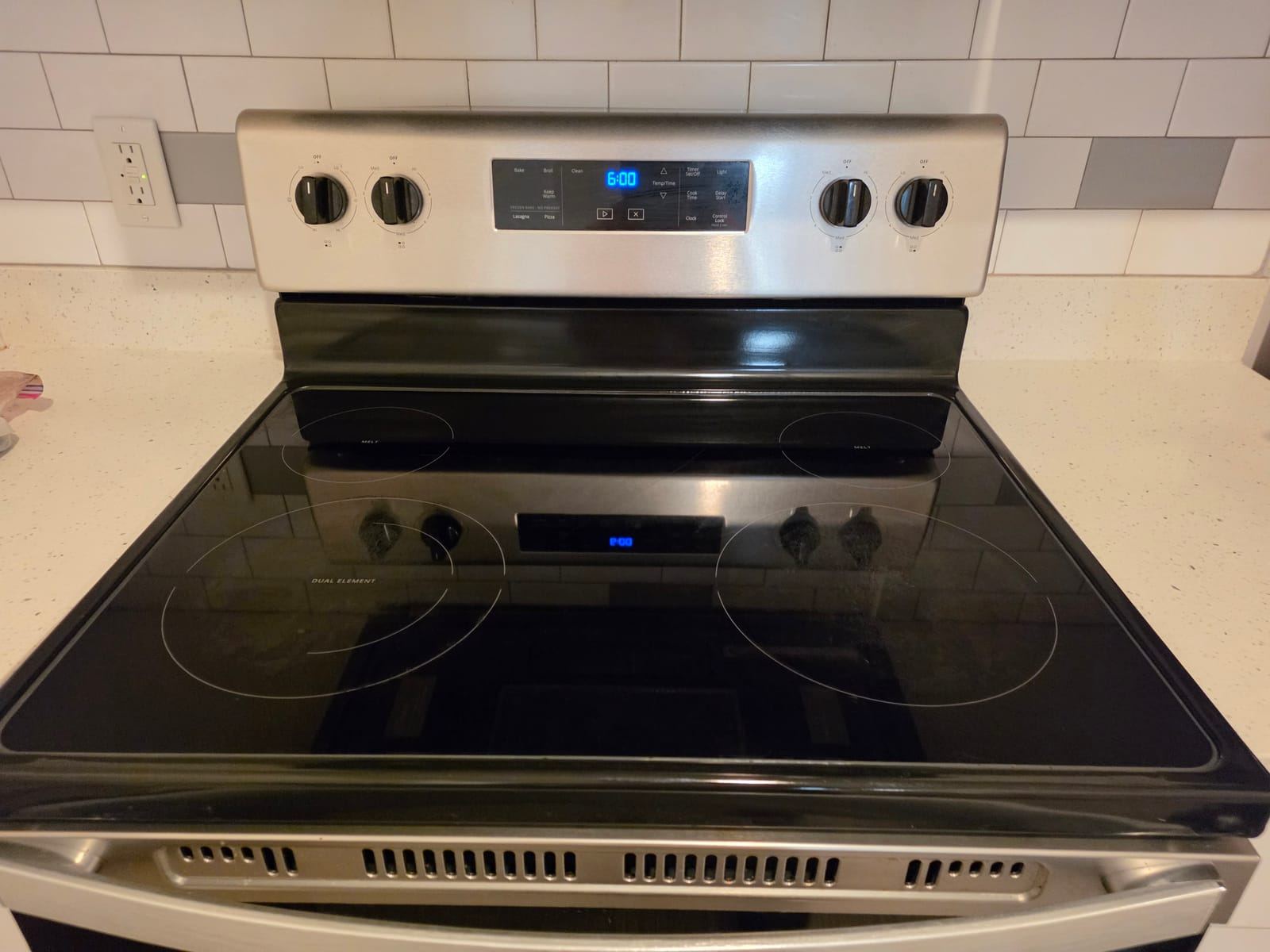 A clean black glass cooktop on a stainless steel range.