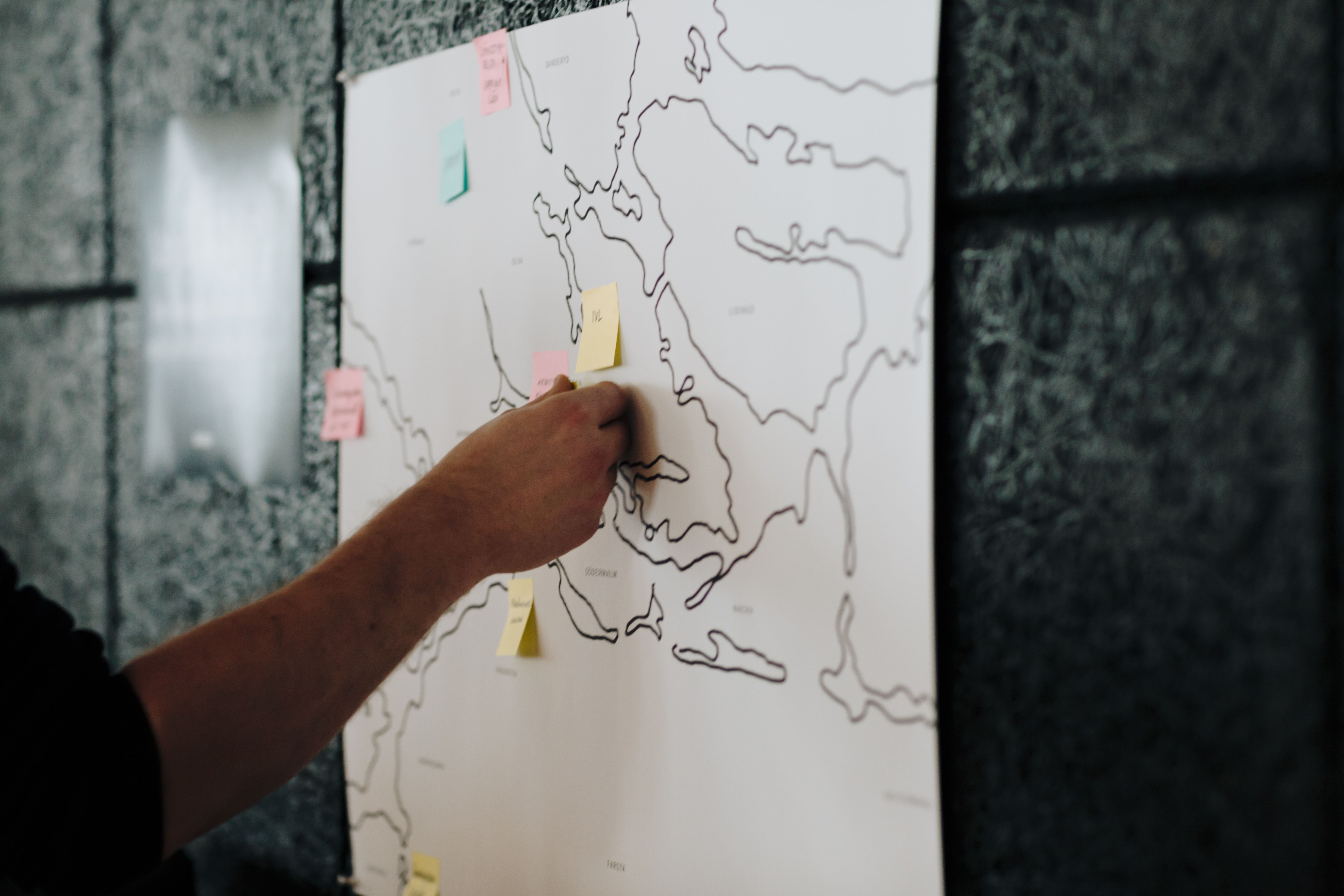 Hand putting post-it notes on a map