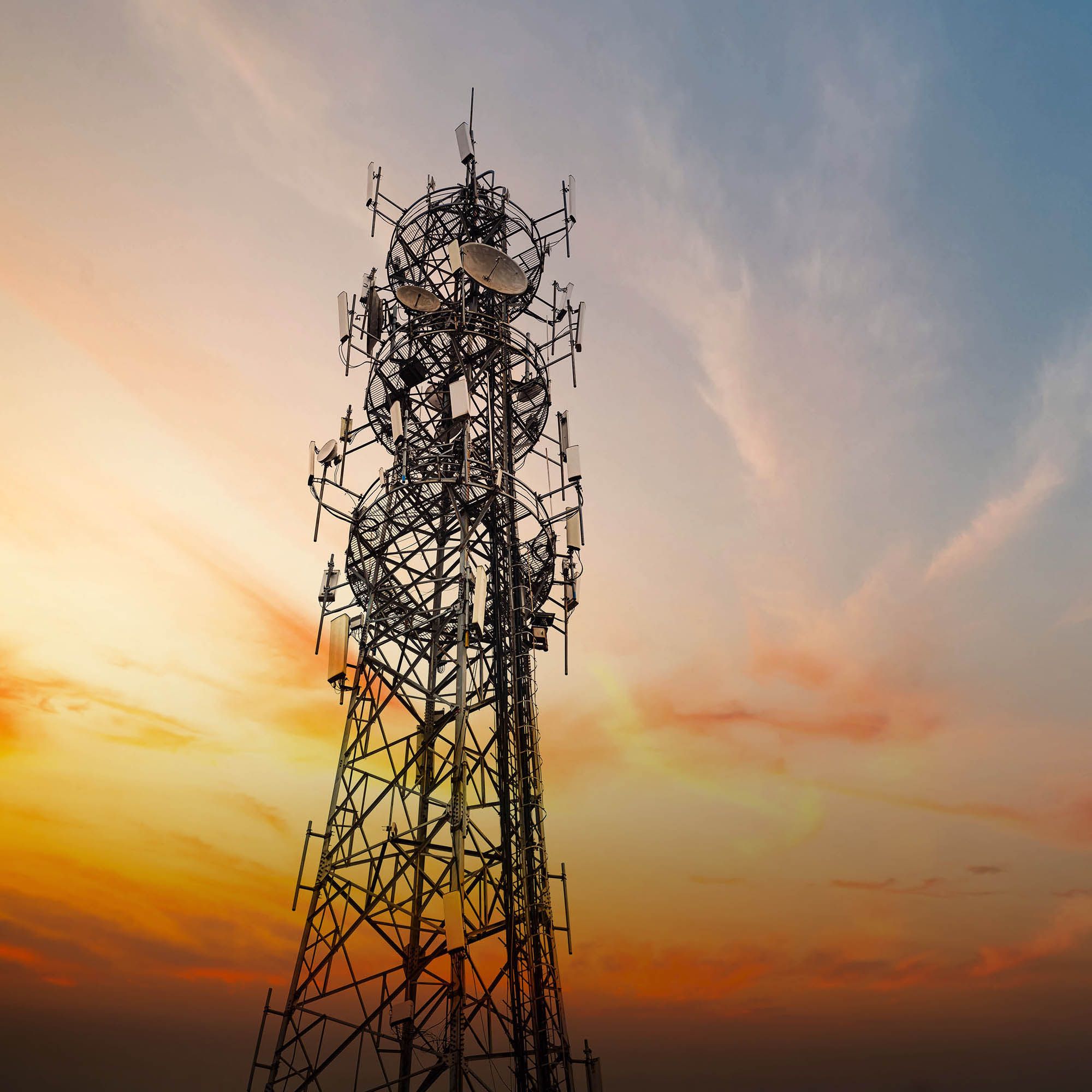 A telecom mast in front of a sunset colored sky