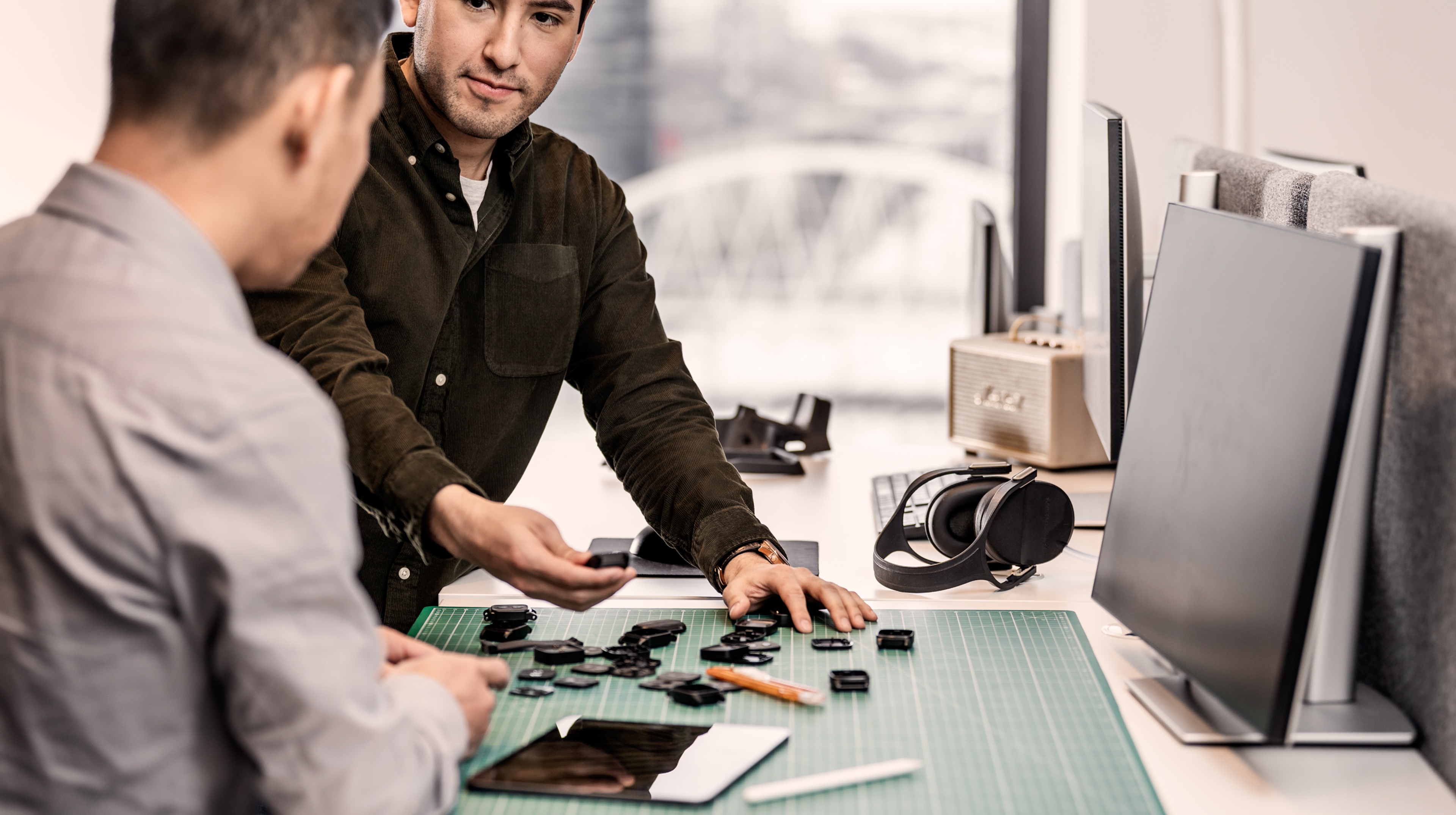 Several watches a prototypes on a table in front of two guys.