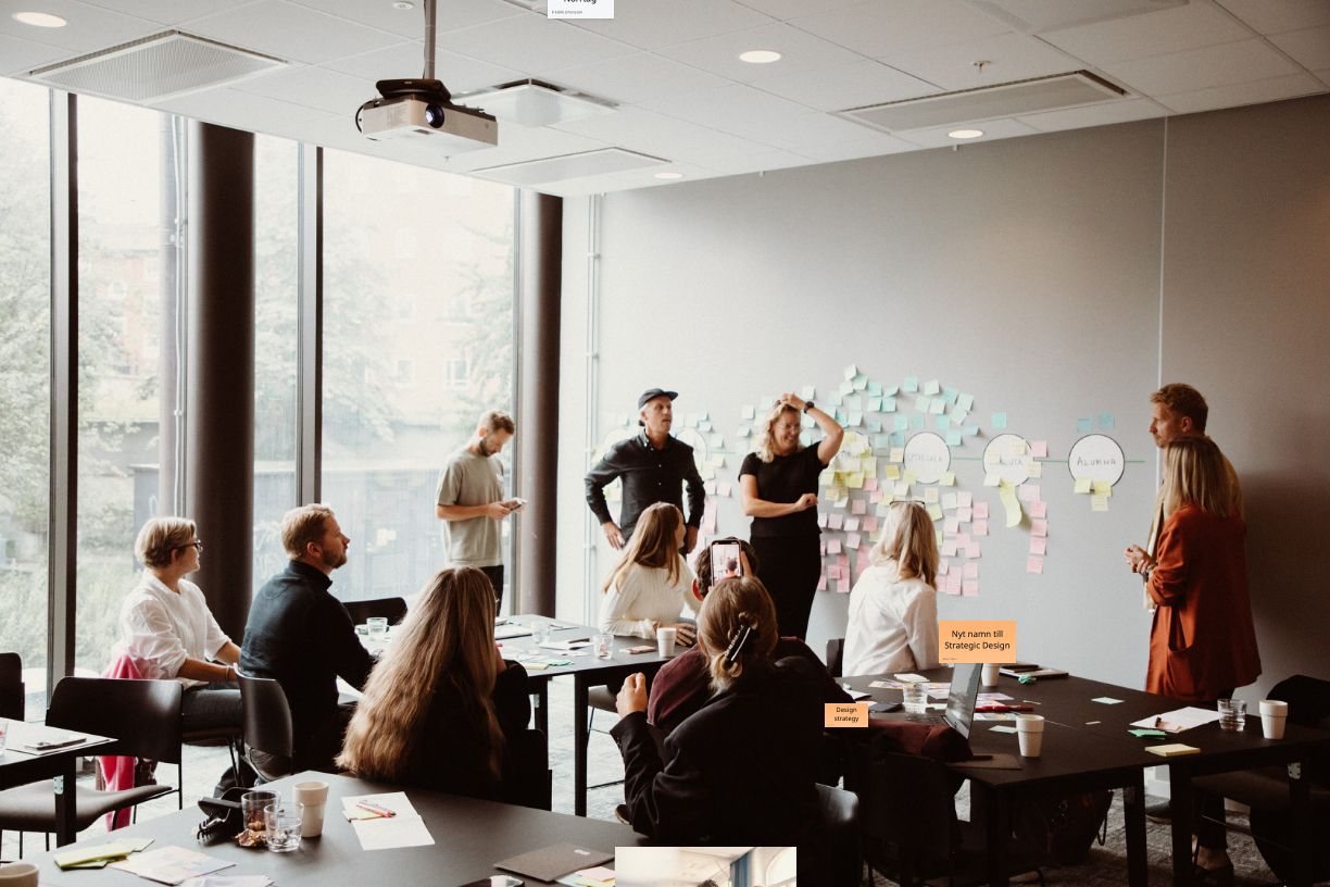 Många personer står framför en whiteboard och har en workshop tillsammans.