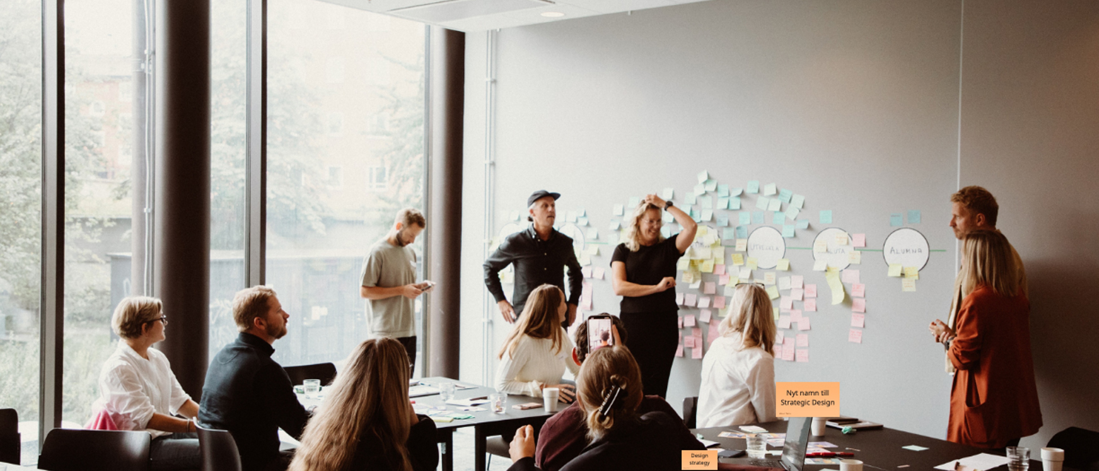 Många personer står framför en whiteboard och har en workshop tillsammans.