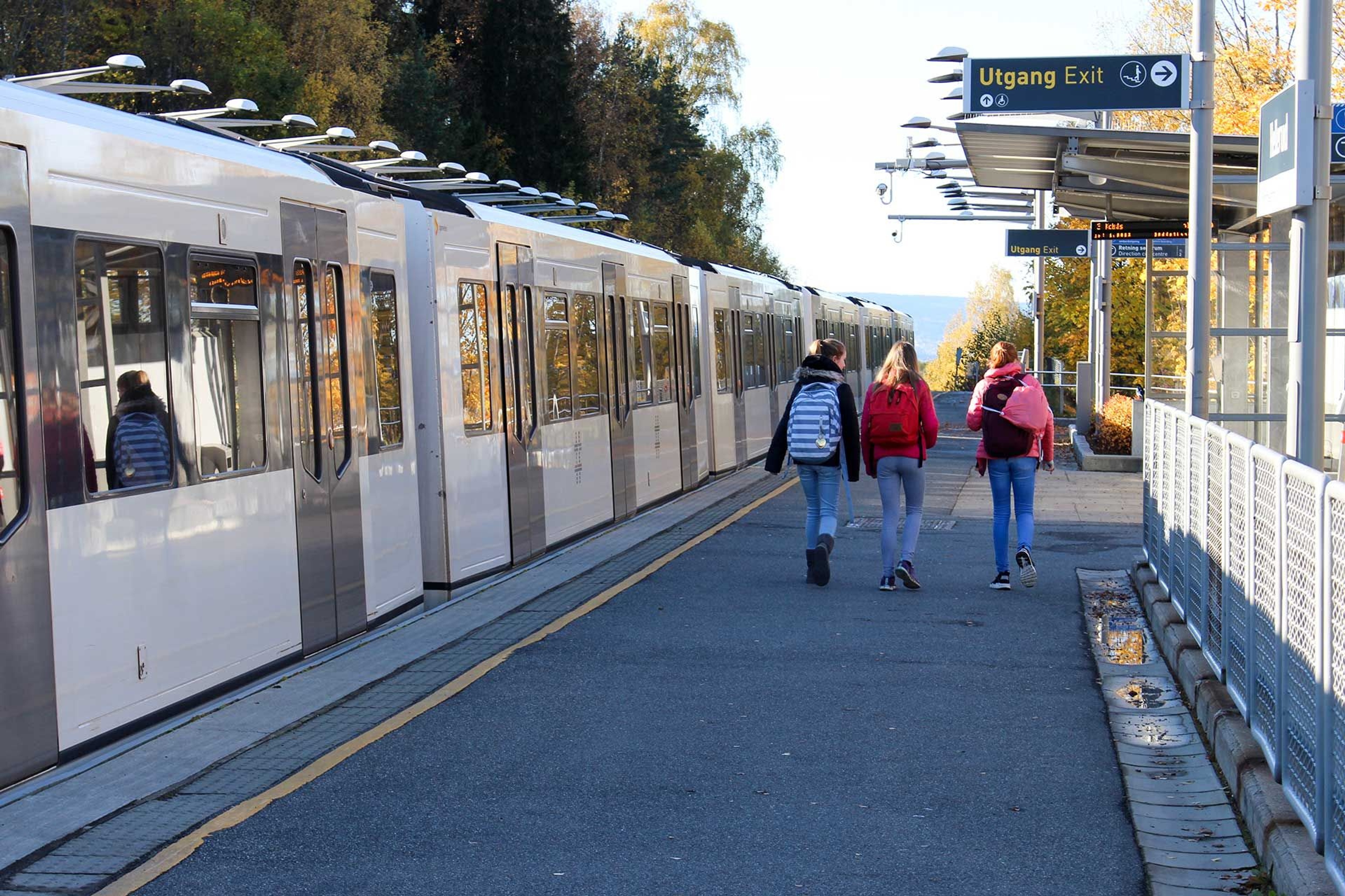 Children walking on a train platform with a train on the side