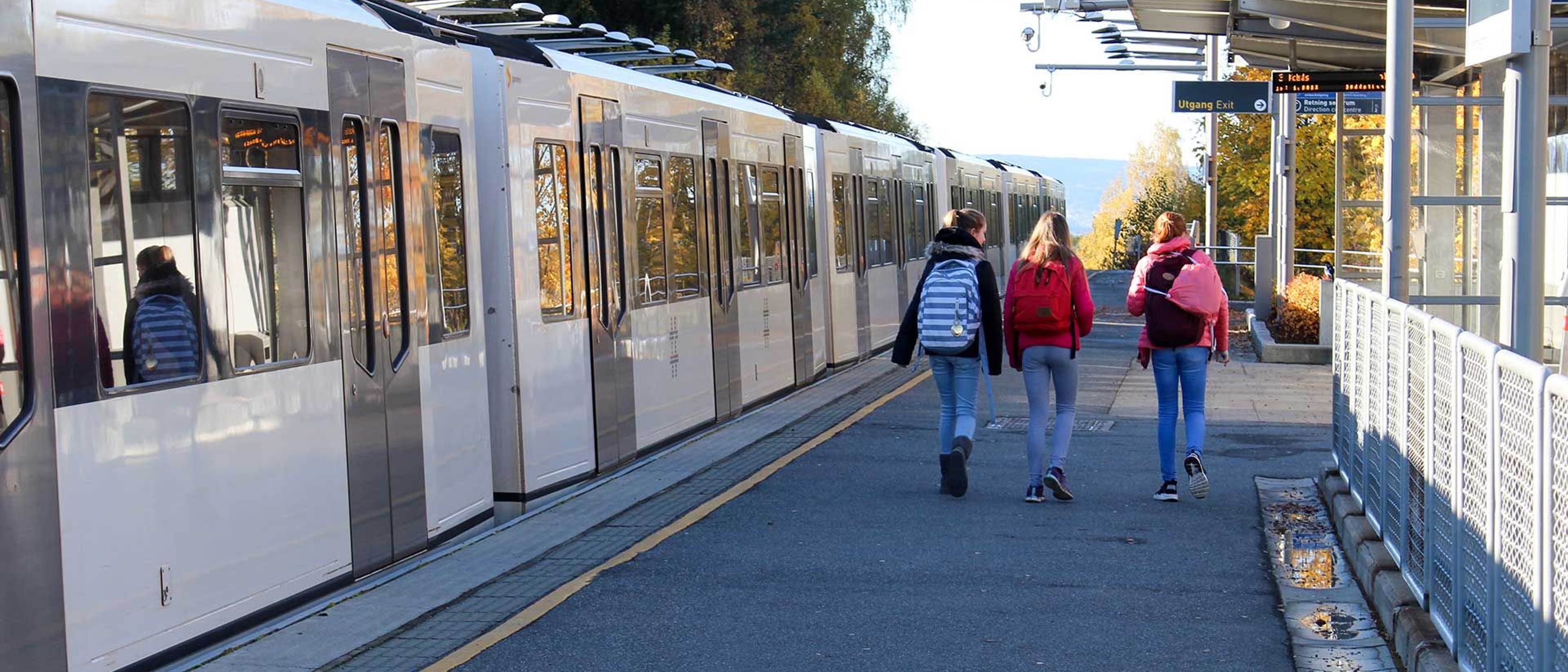 Three girls walkig side-by-side with a train