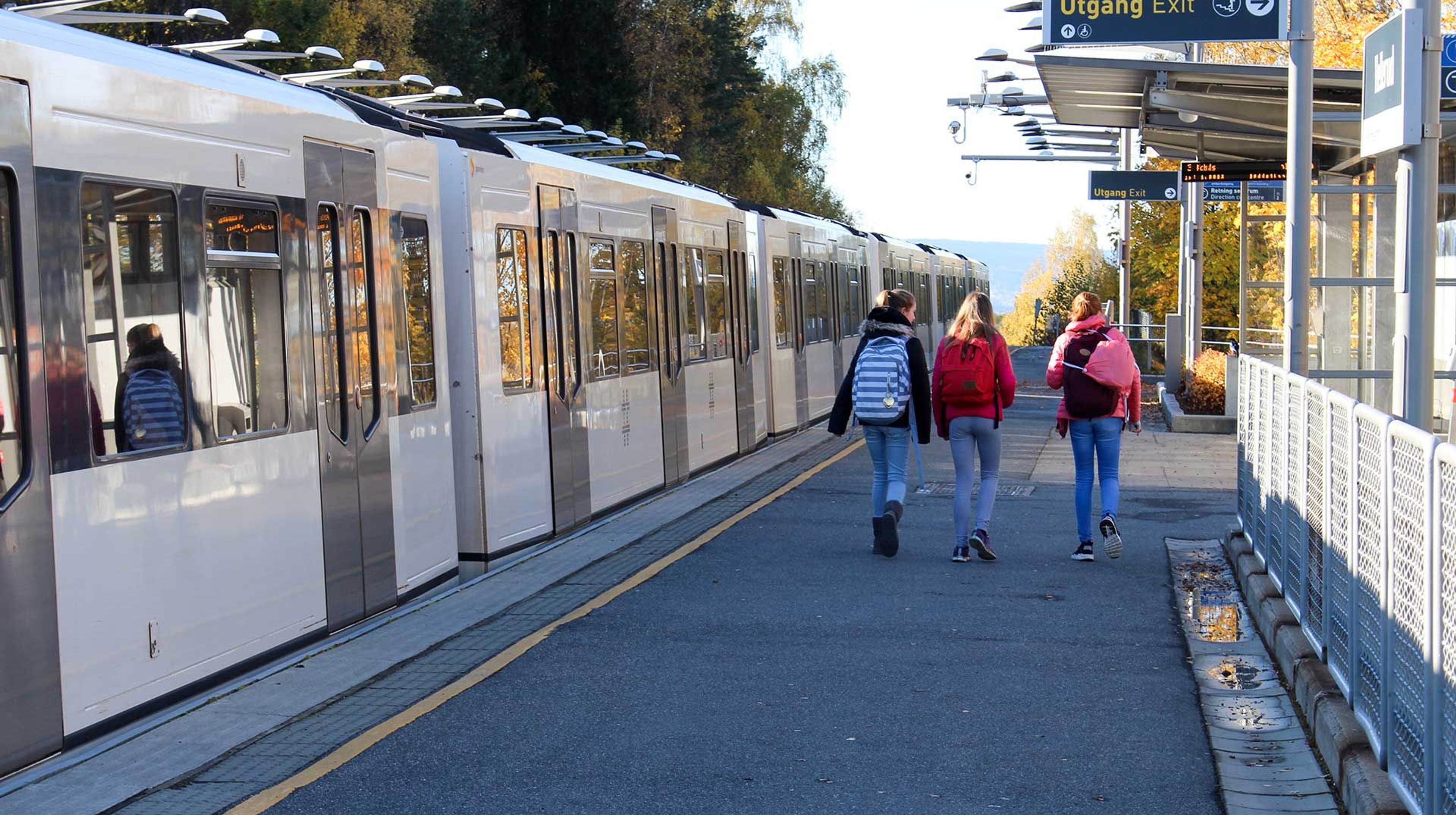 Children walking on a train platform with a train on the side