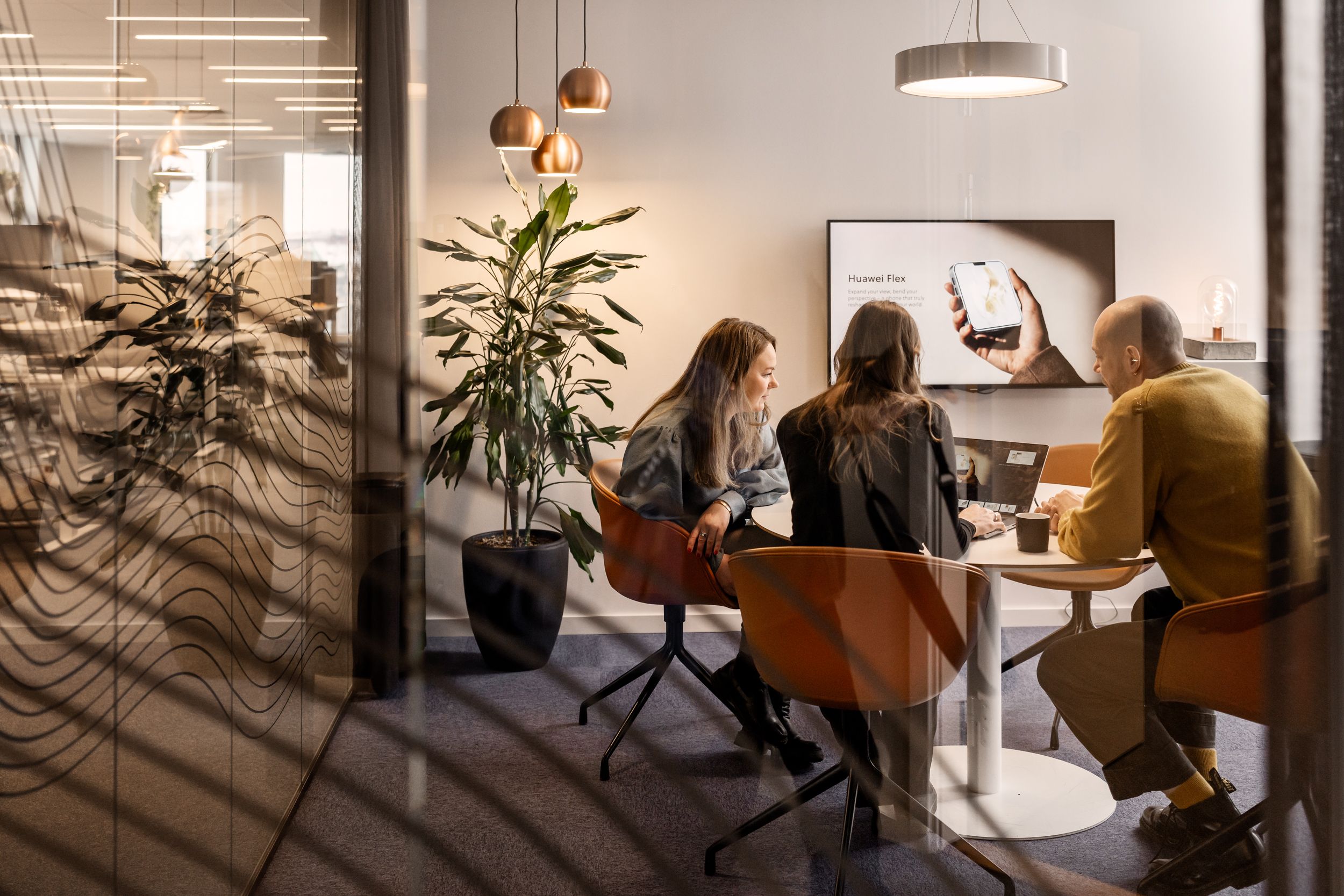 Three people sitting at a conference table talking to each other