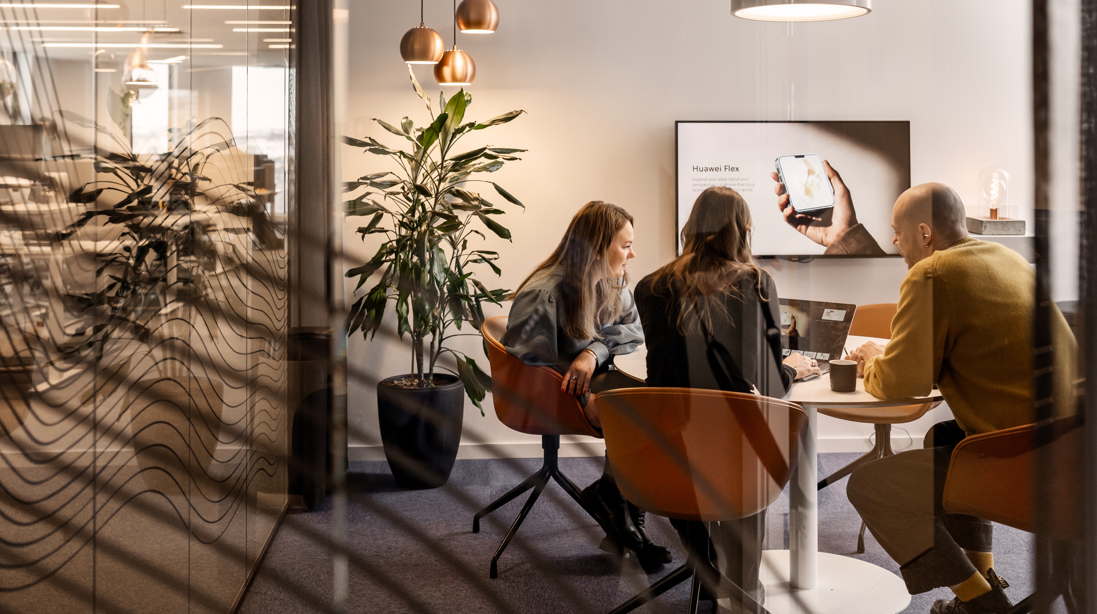 Three people sitting at a conference table talking to each other
