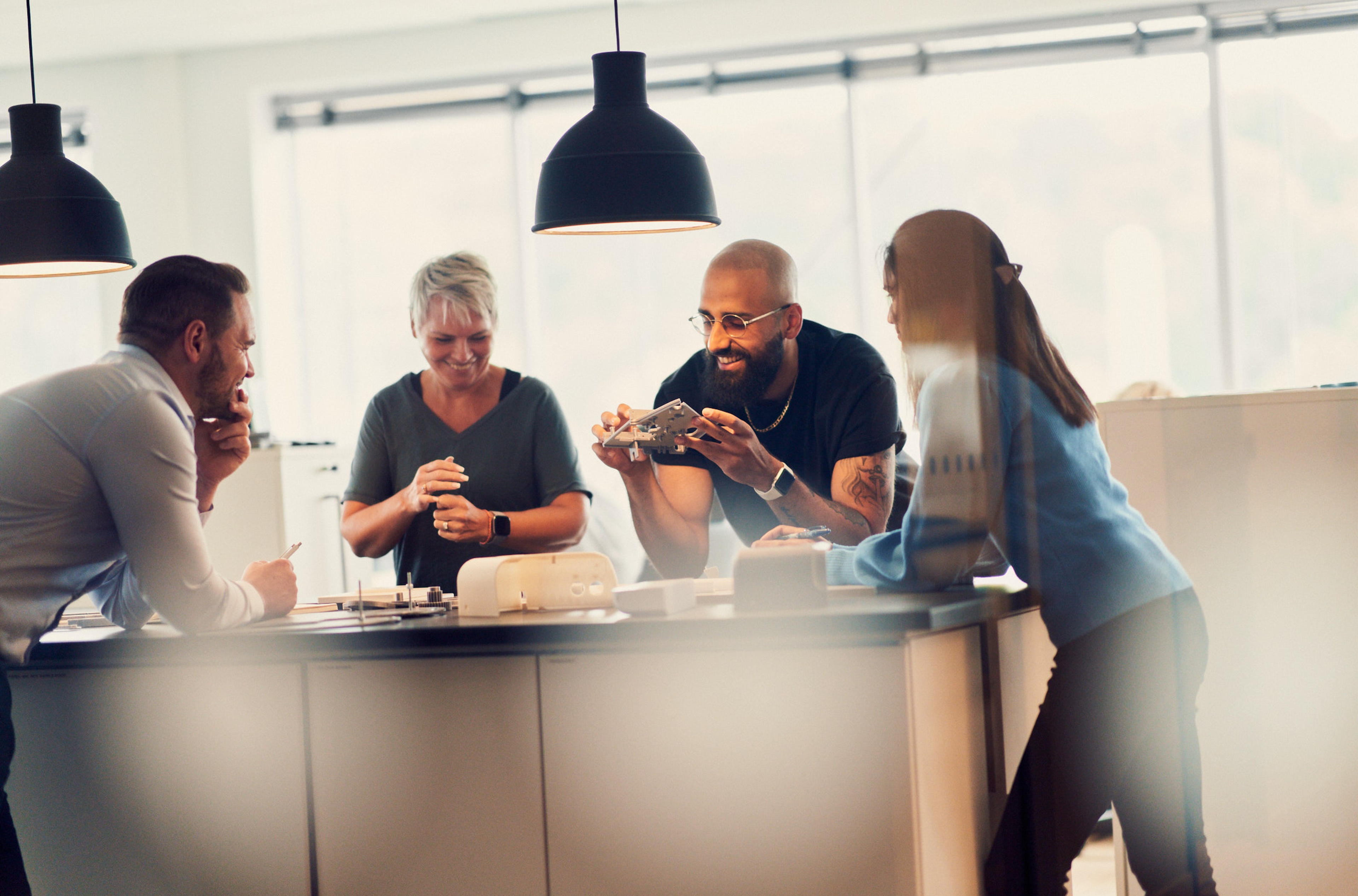 Um grupo de pessoas colaborando em volta de uma mesa com protótipos