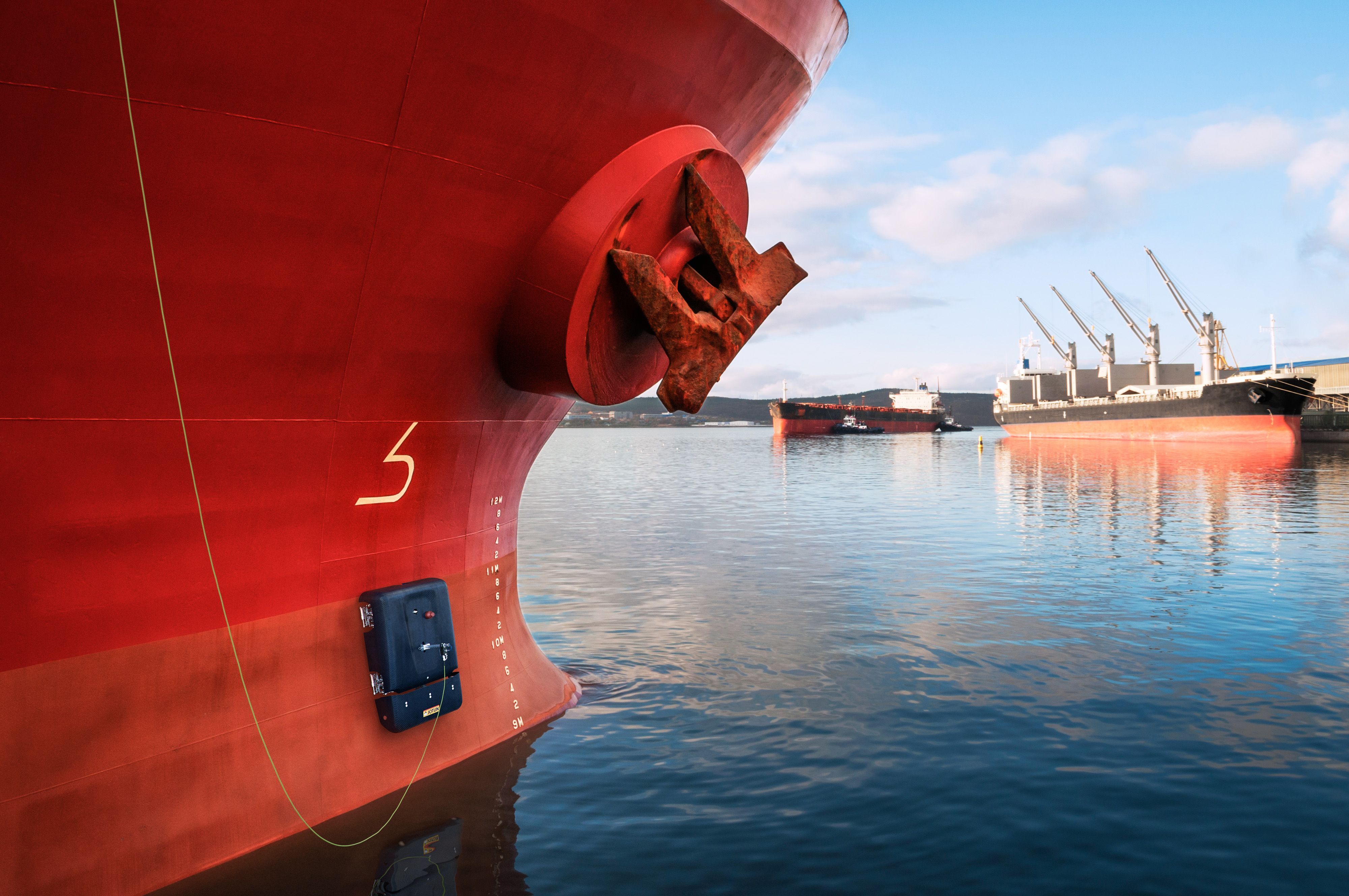 Close-up of a ship’s hull and anchor in a harbor.