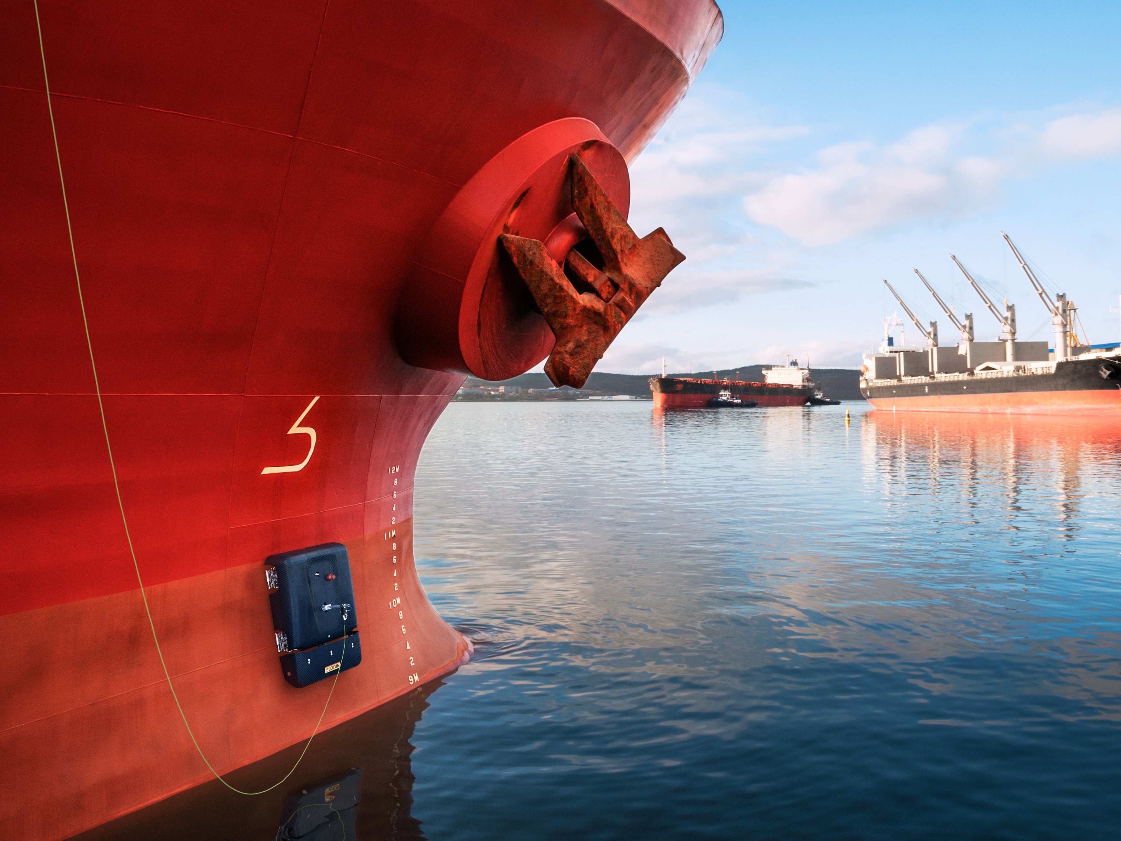 Close-up of a ship’s hull and anchor in a harbor.