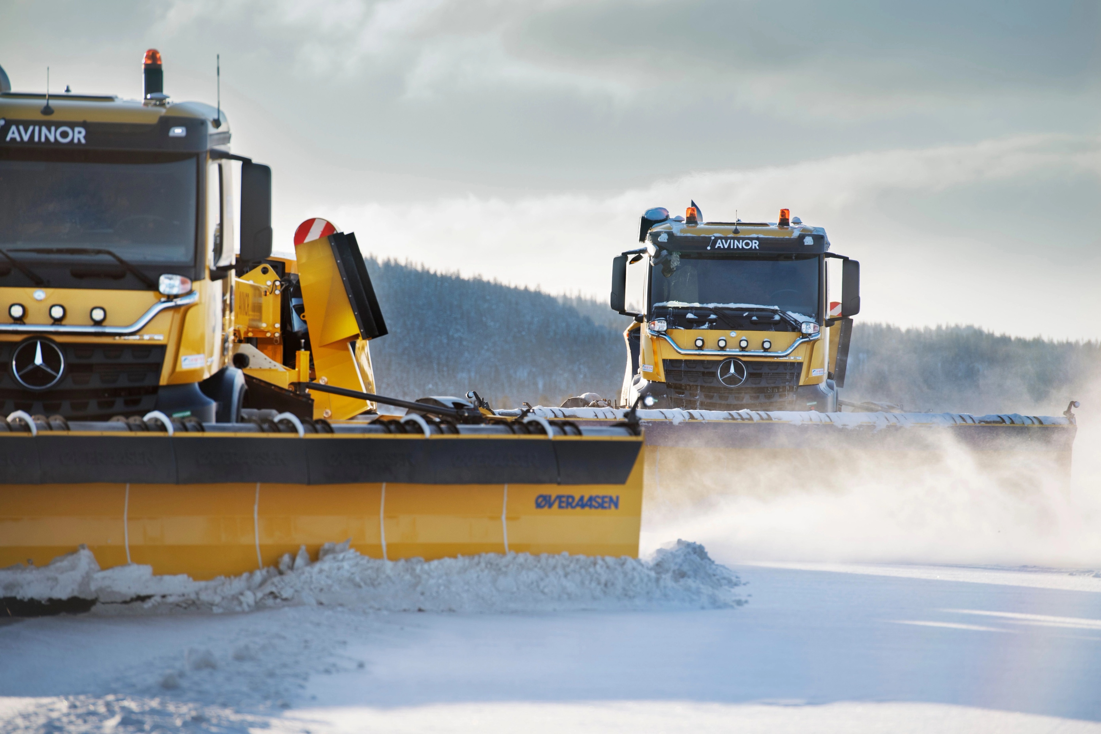 Snowplough vehicles clearing snow from an airport runway.