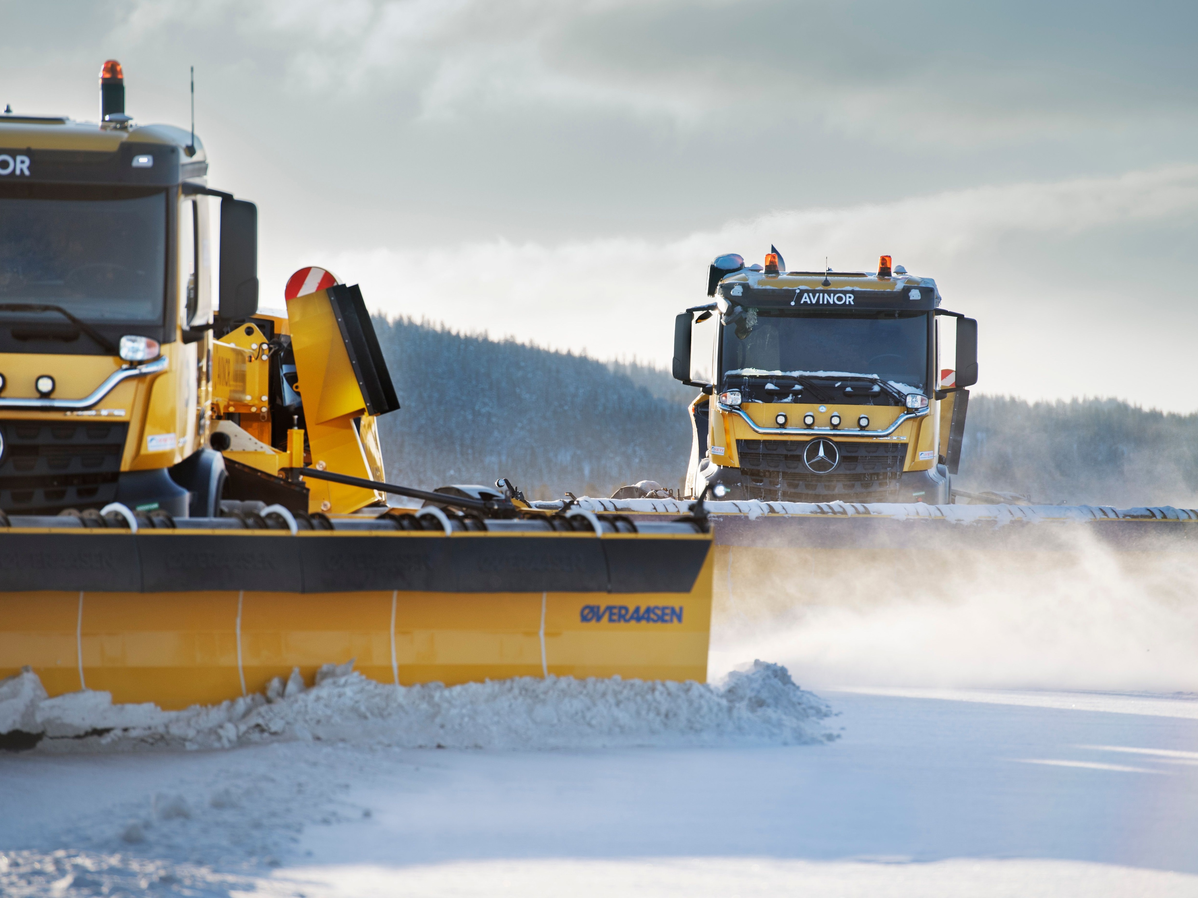 Snowplough vehicles clearing snow from an airport runway.