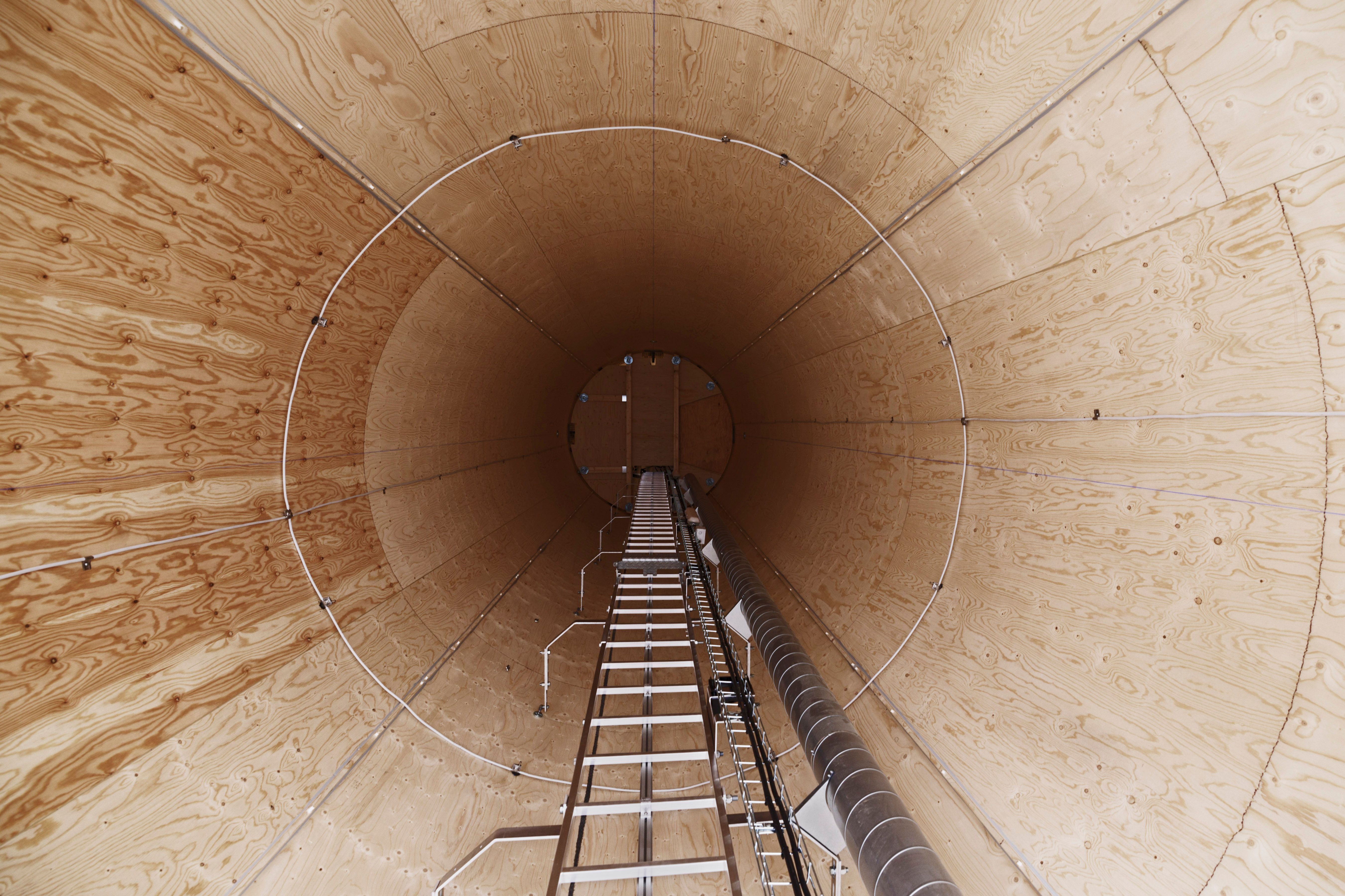 Interior of a tall wooden cylindrical structure with a ladder leading upward.